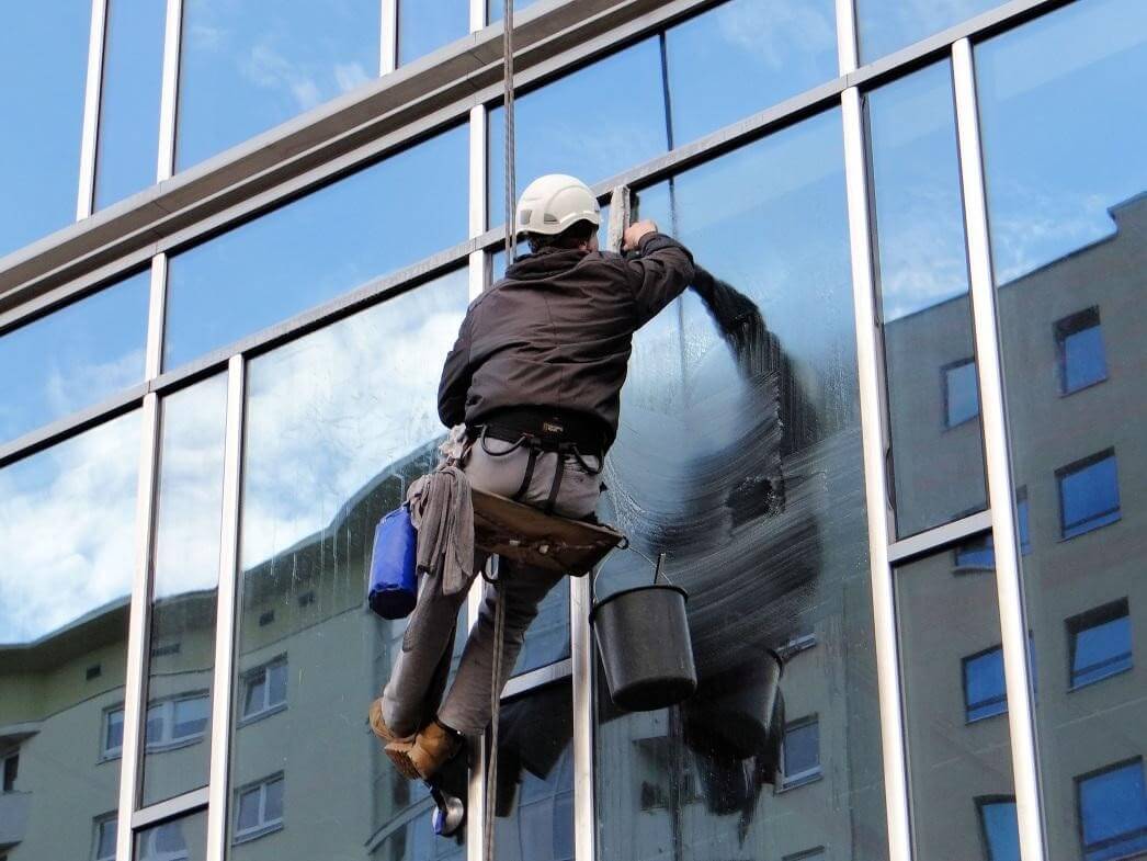 A technician from Window Ninjas Hampton Roads cleaning the exterior windows of a high-rise office building.