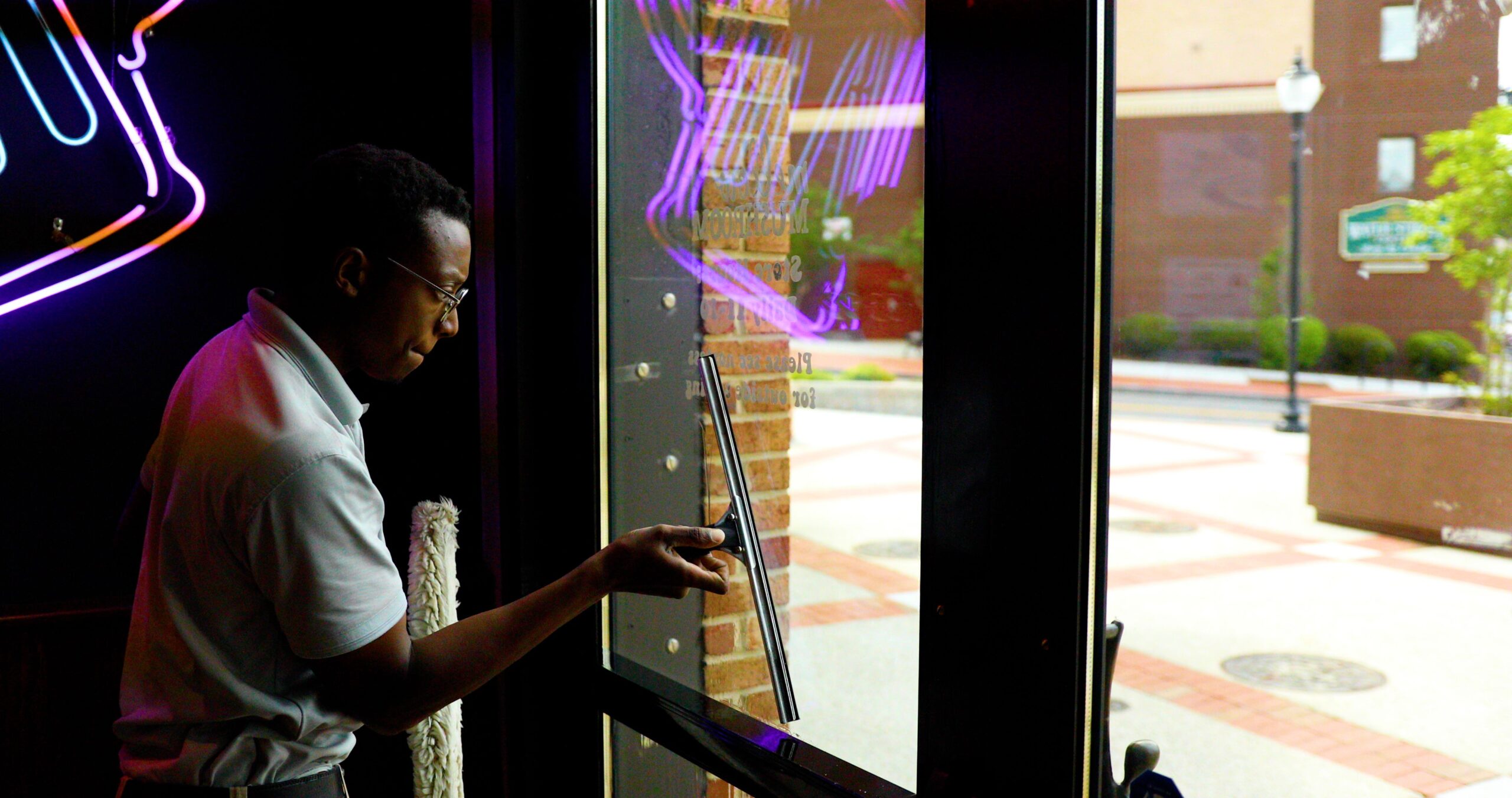 A Window Ninjas expertly cleaning the inside of a business's storefront windows.