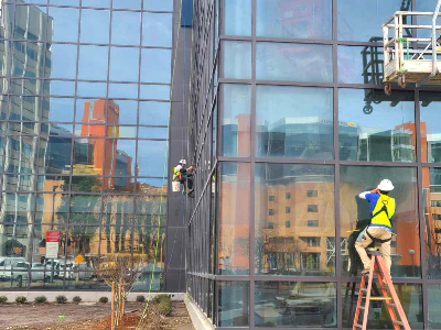 A Window Ninjas professional cleaning windows on the outside of a tall office building - contact us today to discuss our Hampton / Newport News office window cleaning services!