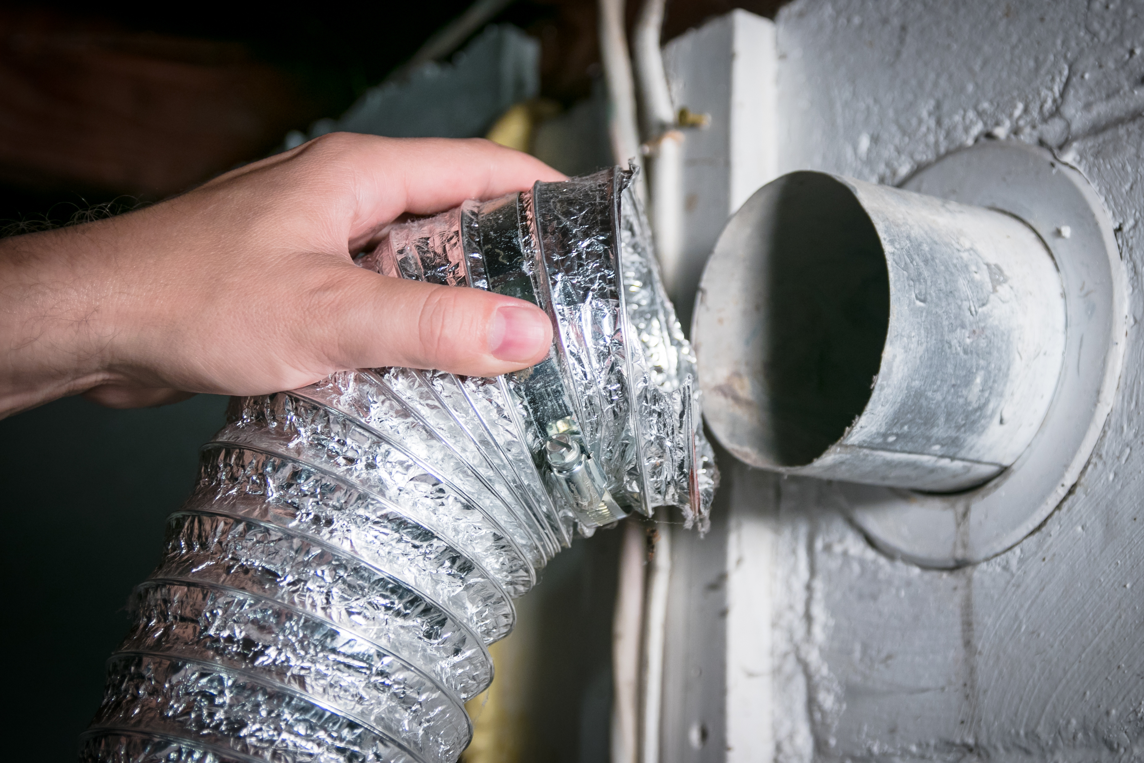 An image showing a Window Ninjas technician cleaning a dryer vent.