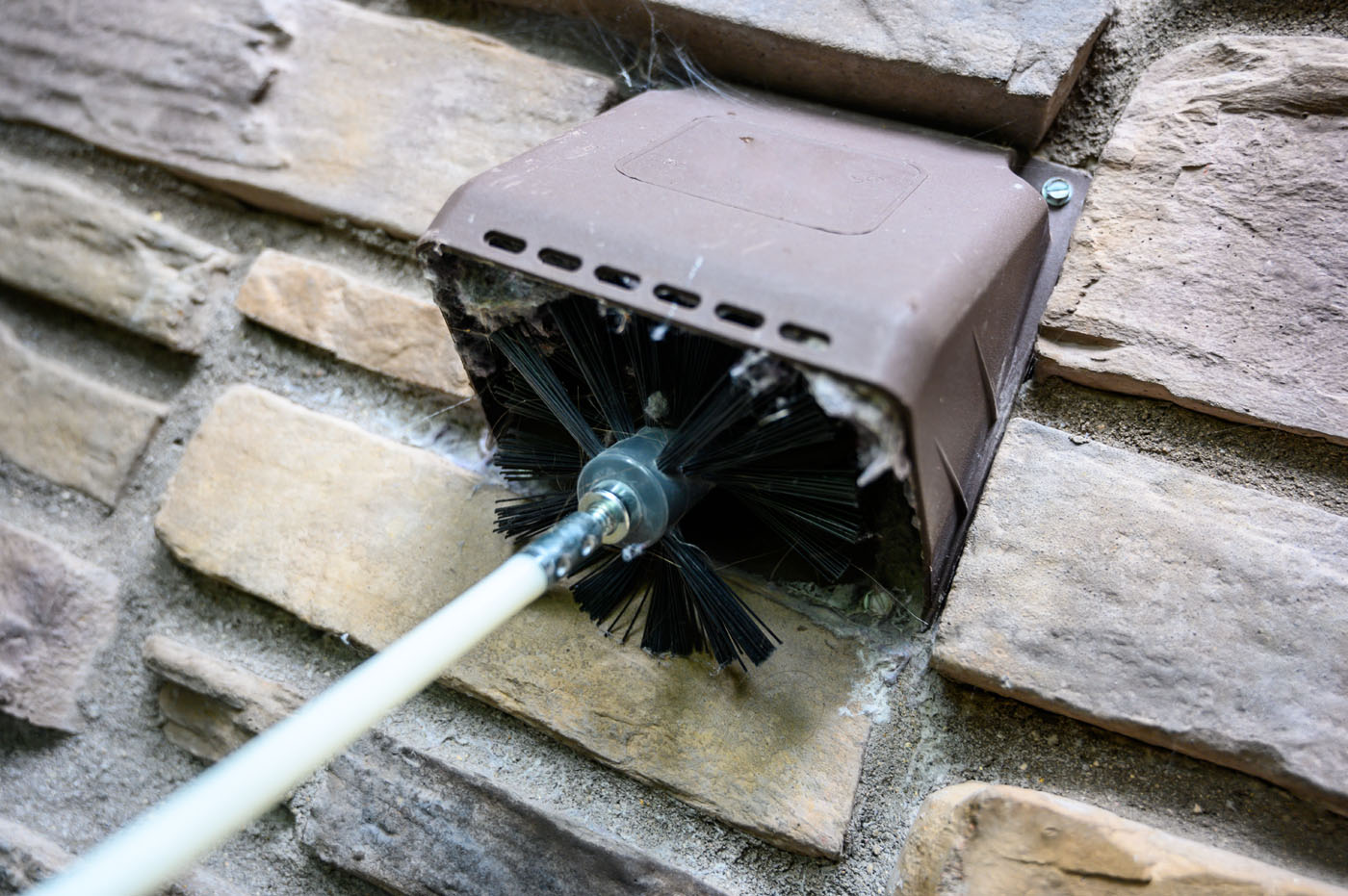 An image of an exterior dryer vent being cleaned by Window Ninjas, the best vent cleaning company.