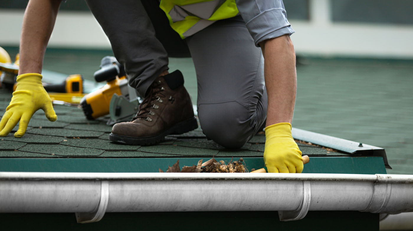 A person cleaning out gutters - for the best gutter cleaning prices, trust Window Ninjas.