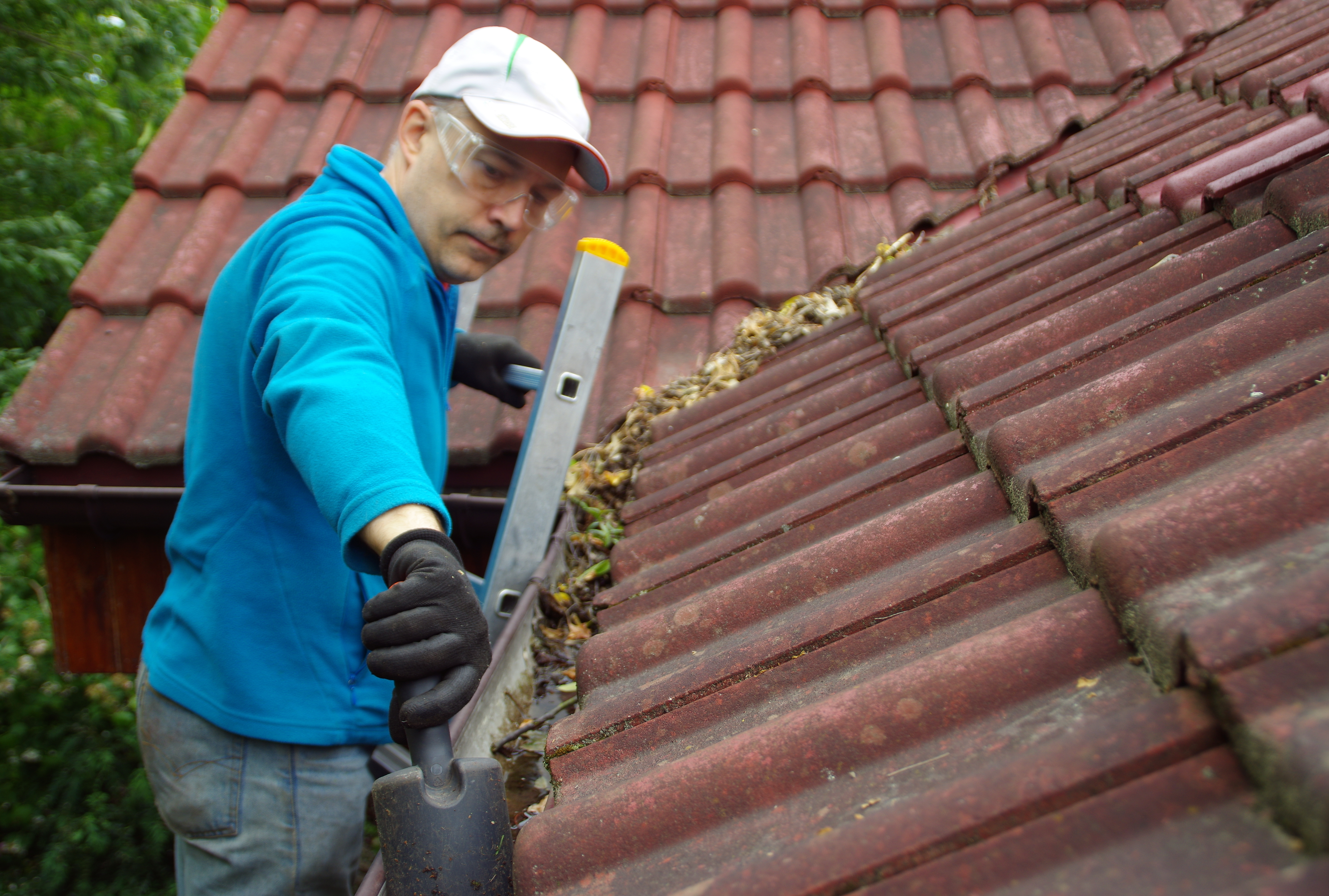 A professional handyman from Window Ninjas cleaning a gutter.