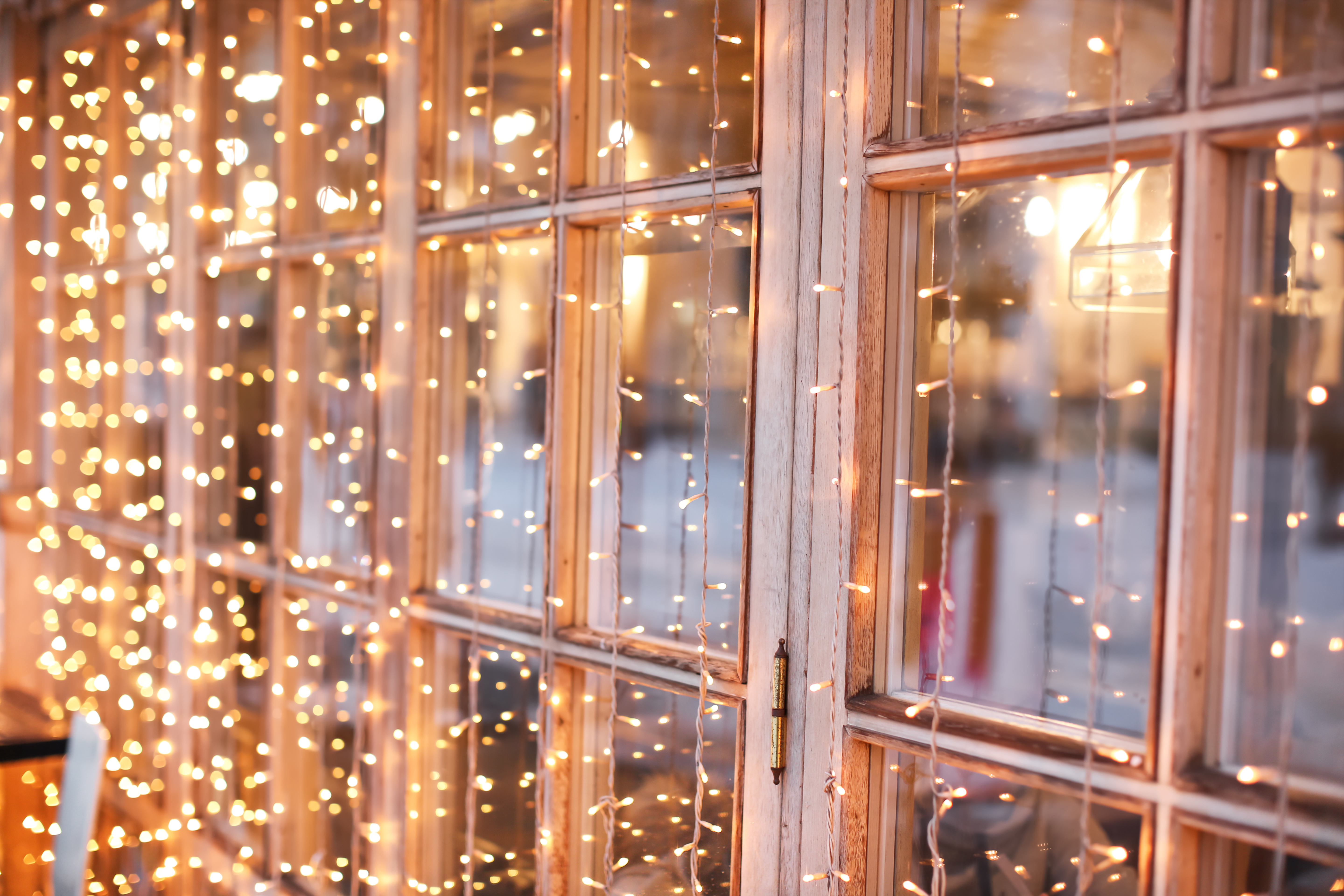 Holiday string lights hanging in front of a home's window - Contact Window Ninjas for residential Christmas light installation in Greenville, NC.