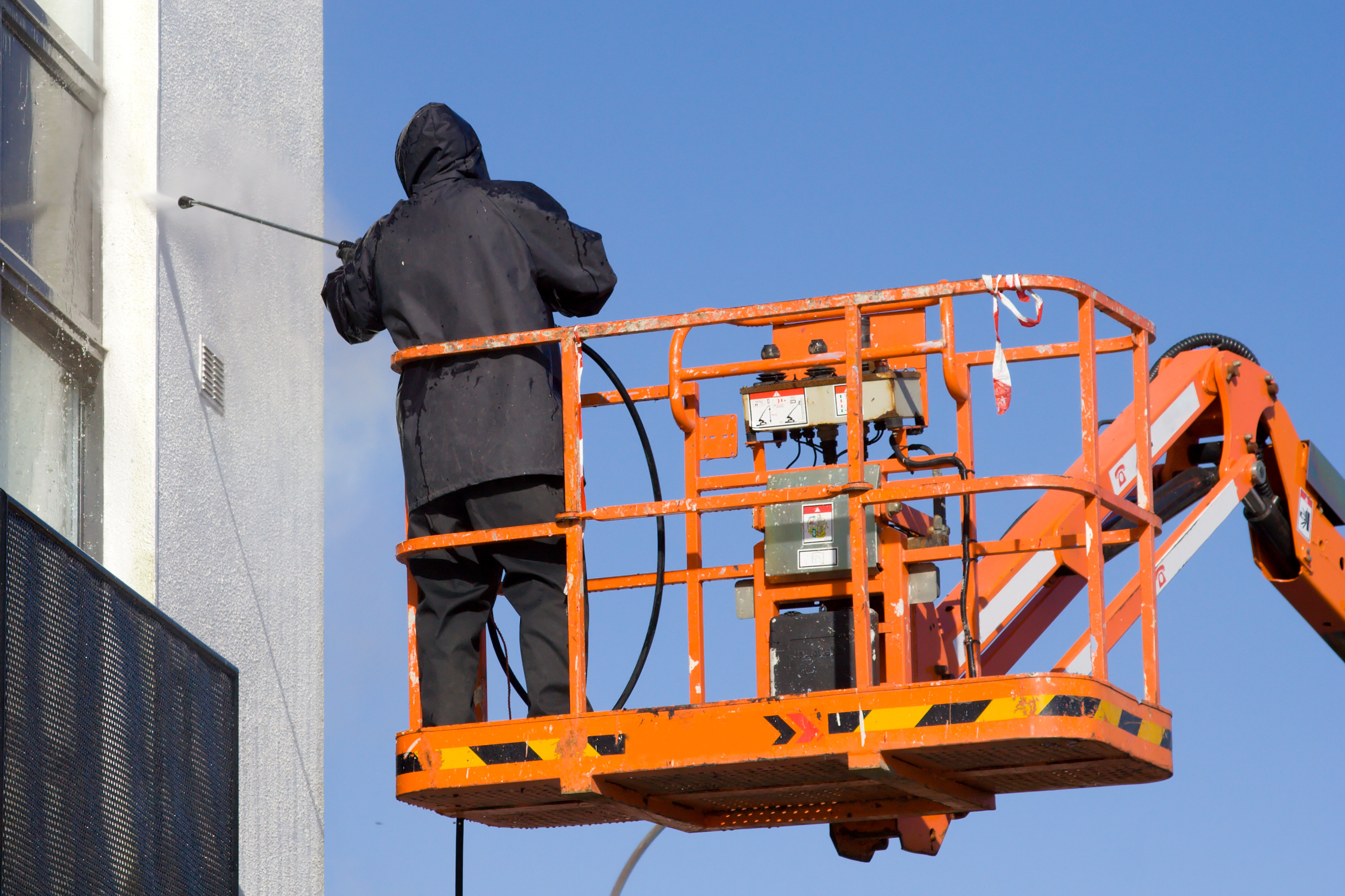 A Window Ninjas team member pressure washing the exterior of a commercial building.