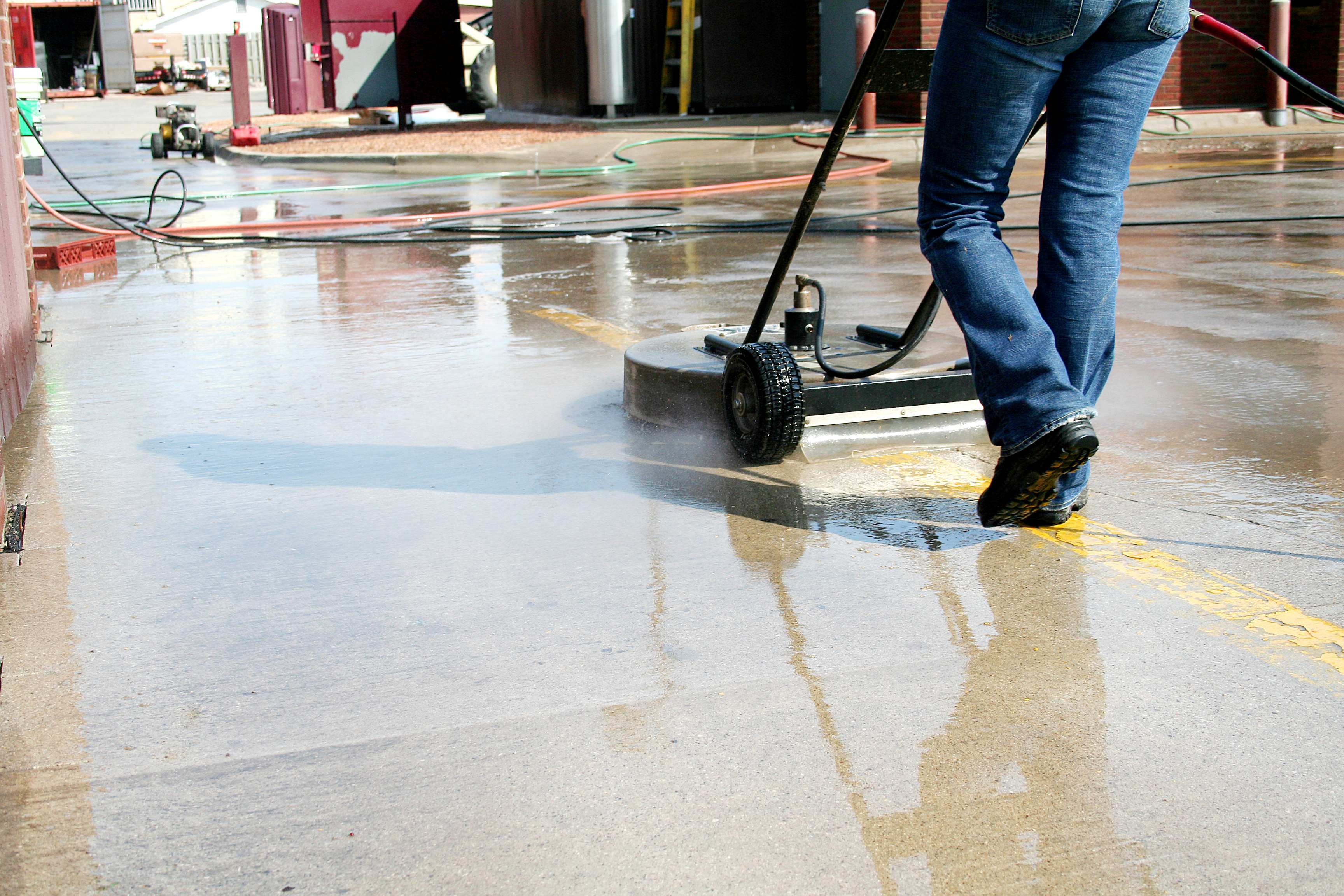 Window Ninjas technician cleaning a commercial property parking lot - we are the best commercial power washing company.