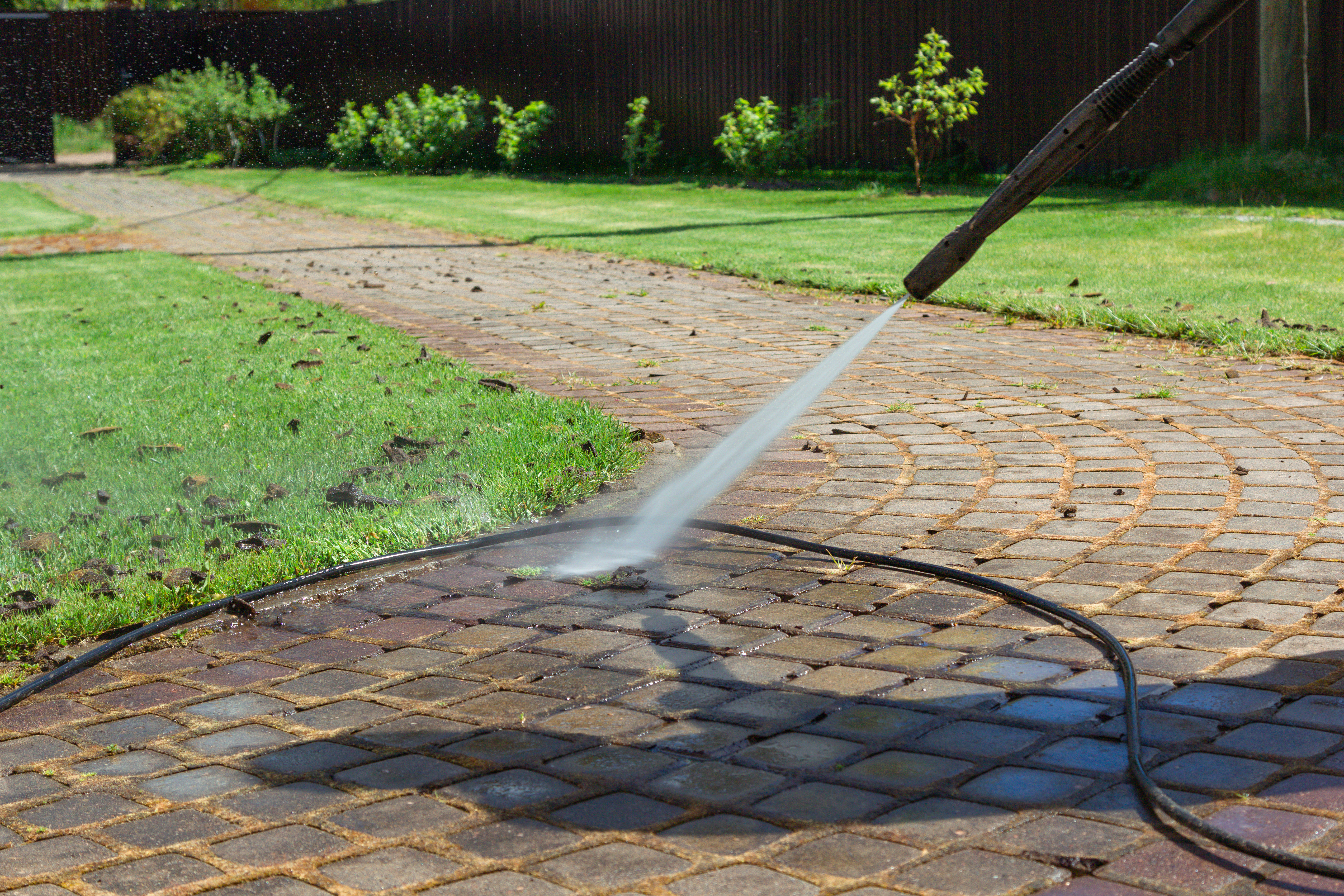 A Window Ninjas pressure washing technician providing sidewalk cleaning.