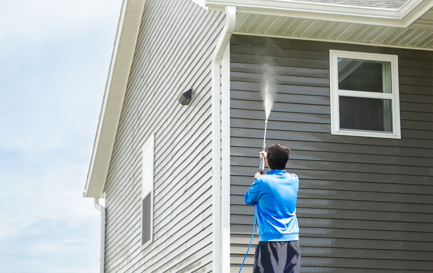 A person cleaning the soffit and roof of a home - book your roof cleaning with Window Ninjas.