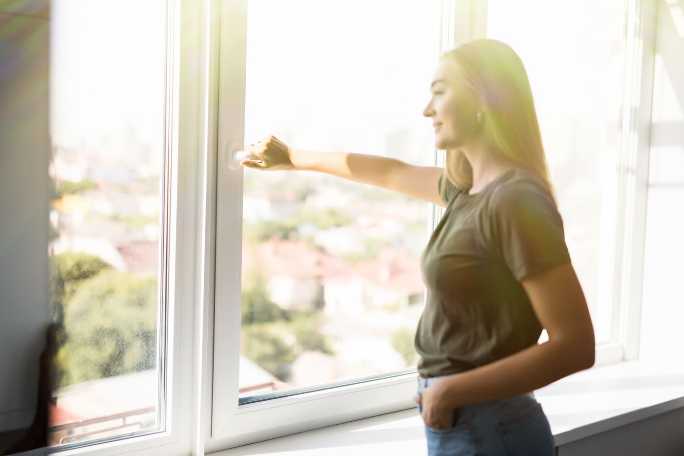 A woman looking out her window - discover the benefits of window cleaning with Window Ninjas and our fair window cleaning rates.