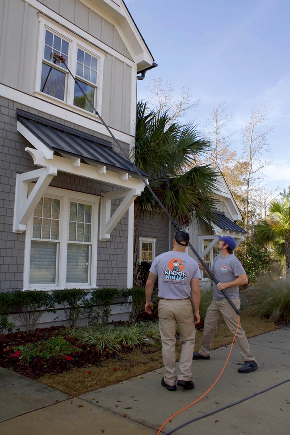 Two Window Ninjas team members washing the windows for a residential home.