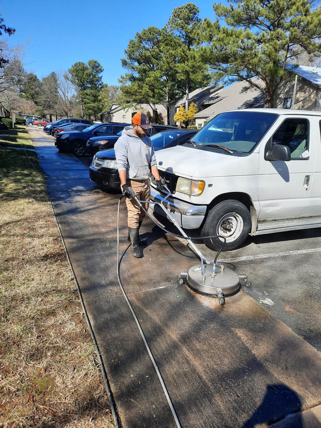 A Window Ninjas employee effectively cleaning a sidewalk with our pressure washing services and advanced technology.