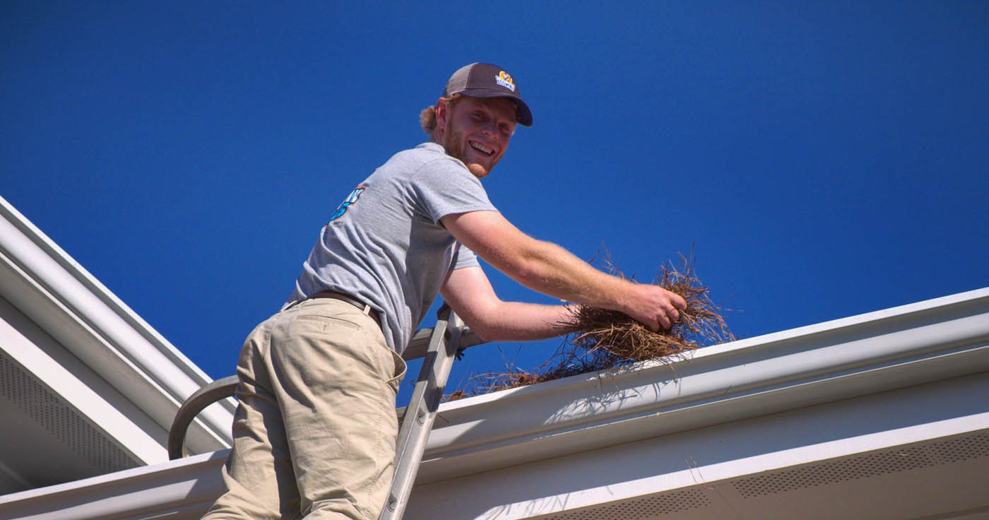 A Window Ninjas technician cleaning a residential gutter.