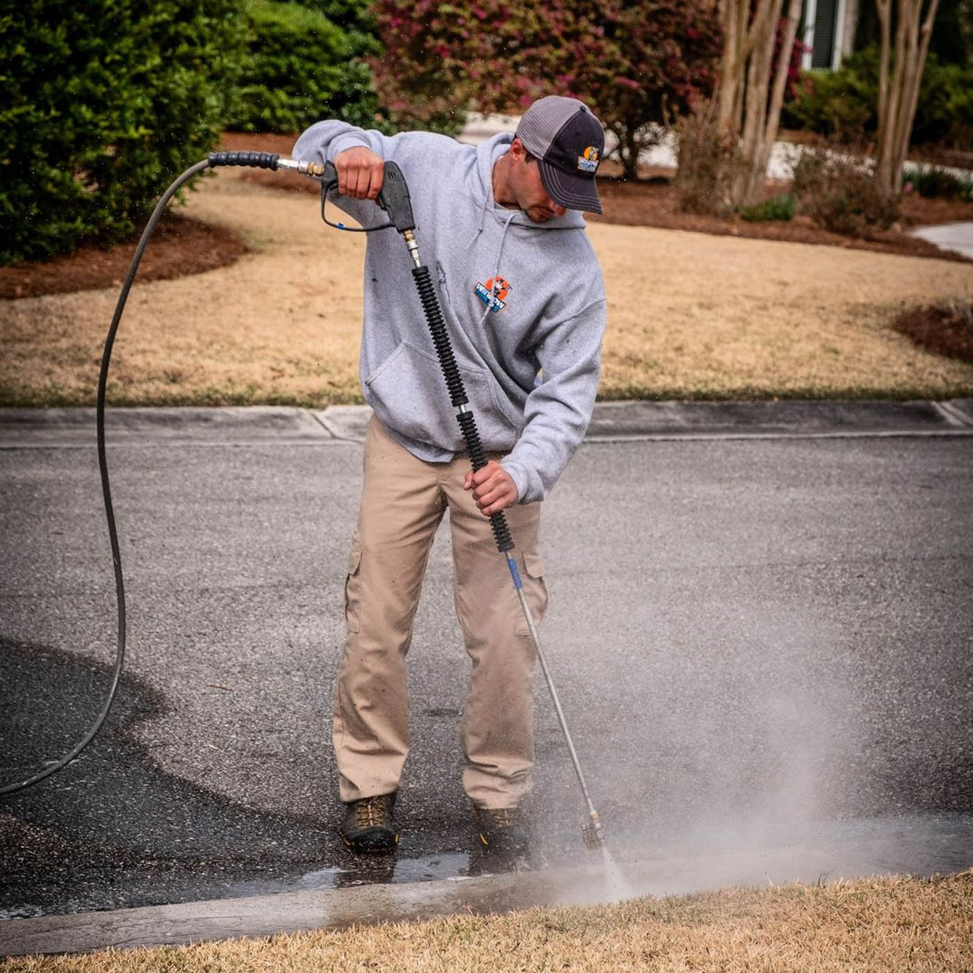 A professional power washer at Window Ninjas cleaning the driveway for a residential property.