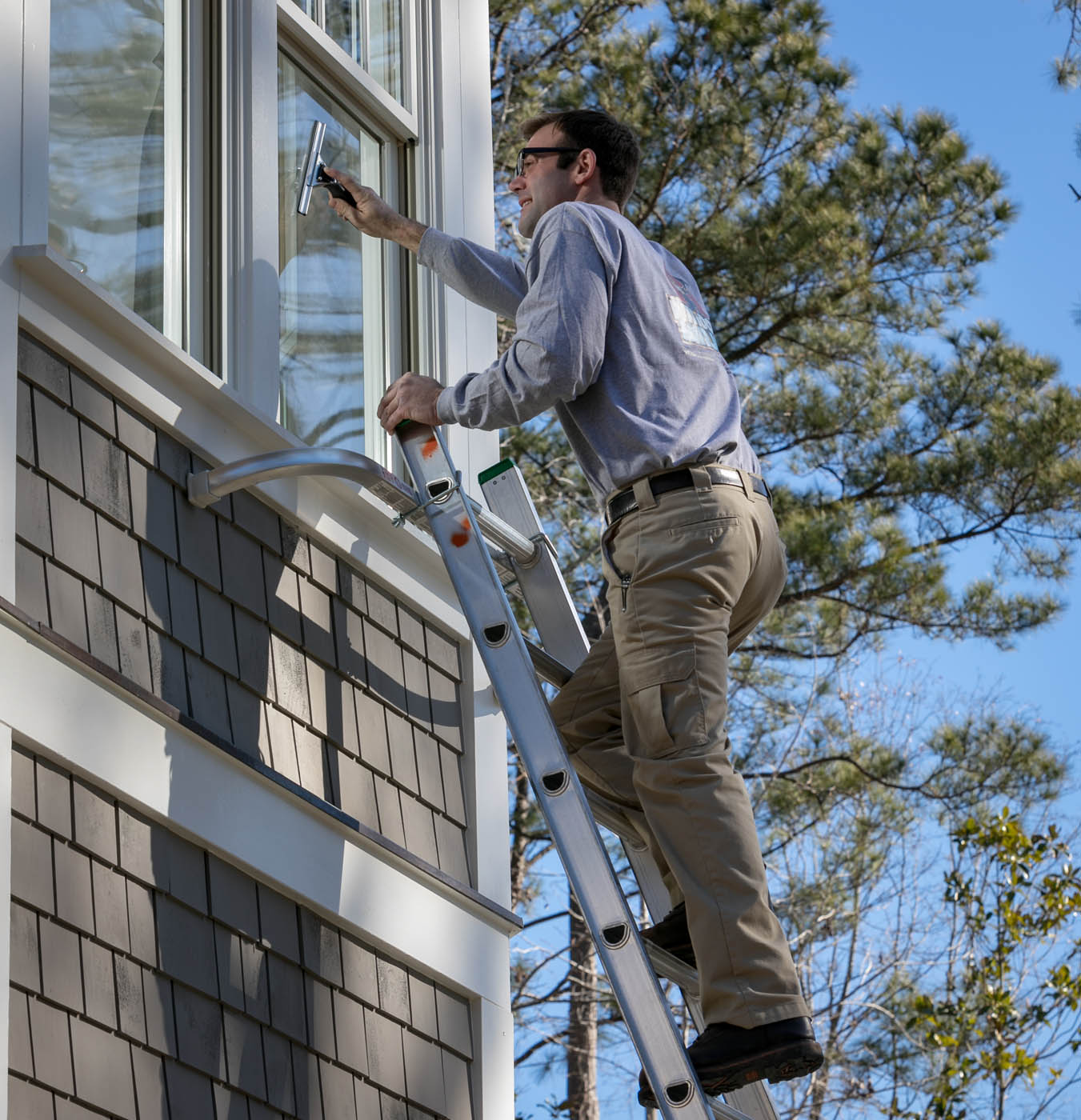 A Window Ninjas window washing technician providing expert cleaning services for a residential home.