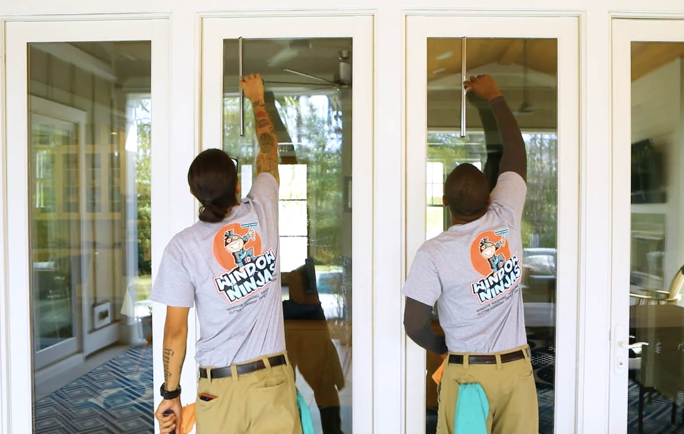 Two Window Ninjas experts providing window cleaning services for the outside of a home.